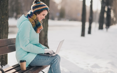 Woman sitting outside on a bench during winter break, working on law school application using JD-Next to help strengthen her resume