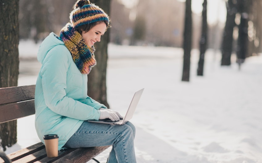 Woman sitting outside on a bench during winter break, working on law school application using JD-Next to help strengthen her resume
